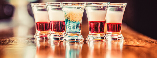 Colorful shots at the club. Alcoholic drink in different colors. Tequila shots, vodka, whisky. Set of alcoholic cocktails in shot glasses