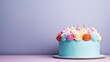  a blue cake with multicolored icing and a single candle sticking out of the top of the cake.