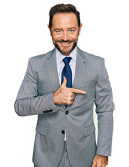 Poster - Middle age man wearing business clothes cheerful with a smile on face pointing with hand and finger up to the side with happy and natural expression