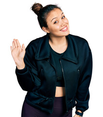 Wall Mural - Young hispanic girl wearing sportswear waiving saying hello happy and smiling, friendly welcome gesture