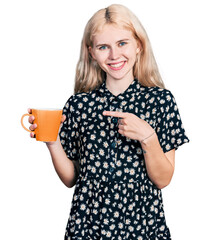 Wall Mural - Young caucasian woman drinking a cup of coffee smiling happy pointing with hand and finger