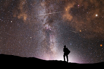 Wall Mural - silhouette of a hiker standing on the hill, on the milky way galaxy background.
