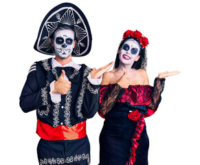 Canvas Print - Young couple wearing mexican day of the dead costume over background showing palm hand and doing ok gesture with thumbs up, smiling happy and cheerful