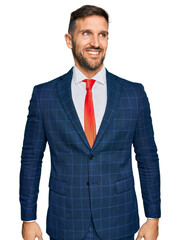 Poster - Handsome man with beard wearing business suit and tie looking away to side with smile on face, natural expression. laughing confident.