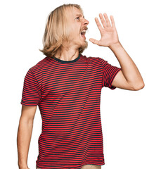 Poster - Caucasian man with blond long hair wearing casual striped t shirt shouting and screaming loud to side with hand on mouth. communication concept.