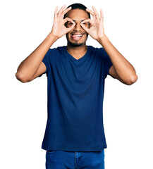 Wall Mural - Young african american man wearing casual t shirt doing ok gesture like binoculars sticking tongue out, eyes looking through fingers. crazy expression.