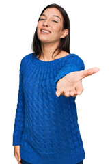 Poster - Young hispanic woman wearing casual clothes smiling cheerful offering palm hand giving assistance and acceptance.