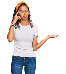 Canvas Print - Young african american girl wearing casual clothes confused and annoyed with open palm showing copy space and pointing finger to forehead. think about it.