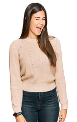 Poster - Young brunette woman wearing casual winter sweater winking looking at the camera with sexy expression, cheerful and happy face.