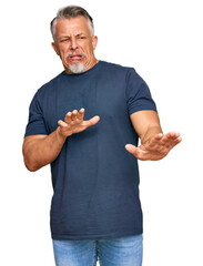 Canvas Print - Middle age grey-haired man wearing casual clothes disgusted expression, displeased and fearful doing disgust face because aversion reaction. with hands raised