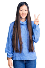 Canvas Print - Young beautiful chinese woman wearing casual turtleneck sweater showing and pointing up with fingers number two while smiling confident and happy.