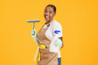 © Prostock-studio - African housekeeper woman holding spray and squeegee over yellow background