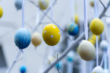 Colorful handmade egges for easter in branches outdoor. Decorating trees with hanging eastereggs in city street. Tradition holiday on christianity religion. Symbol of resurrection to new life.