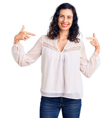 Wall Mural - Young beautiful hispanic woman wearing casual clothes looking confident with smile on face, pointing oneself with fingers proud and happy.