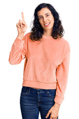 Sticker - Young beautiful hispanic woman wearing casual clothes showing and pointing up with finger number one while smiling confident and happy.