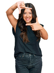 Poster - Beautiful brunette young woman wearing black shirt smiling making frame with hands and fingers with happy face. creativity and photography concept.