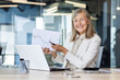 © Liubomir - Portrait of a smiling senior successful business woman sitting in the office at the table, holding and showing documents and graphs to the camera.