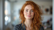 Beautiful amazing young  redheaded smiled  woman at home. Blue eyes and long wavy red hair. Looking forward. 