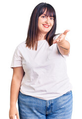 Wall Mural - Young plus size woman wearing casual clothes smiling cheerful offering palm hand giving assistance and acceptance.