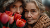 Fototapeta  - Młoda dziewczyna ze starszą kobietą pozują do zdjęcia z kwiatami. 