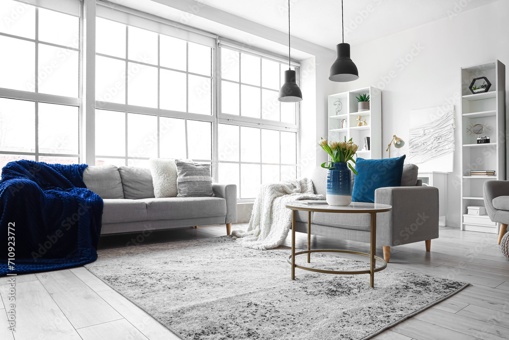 Interior of bright living room with cozy sofas and coffee table near big window