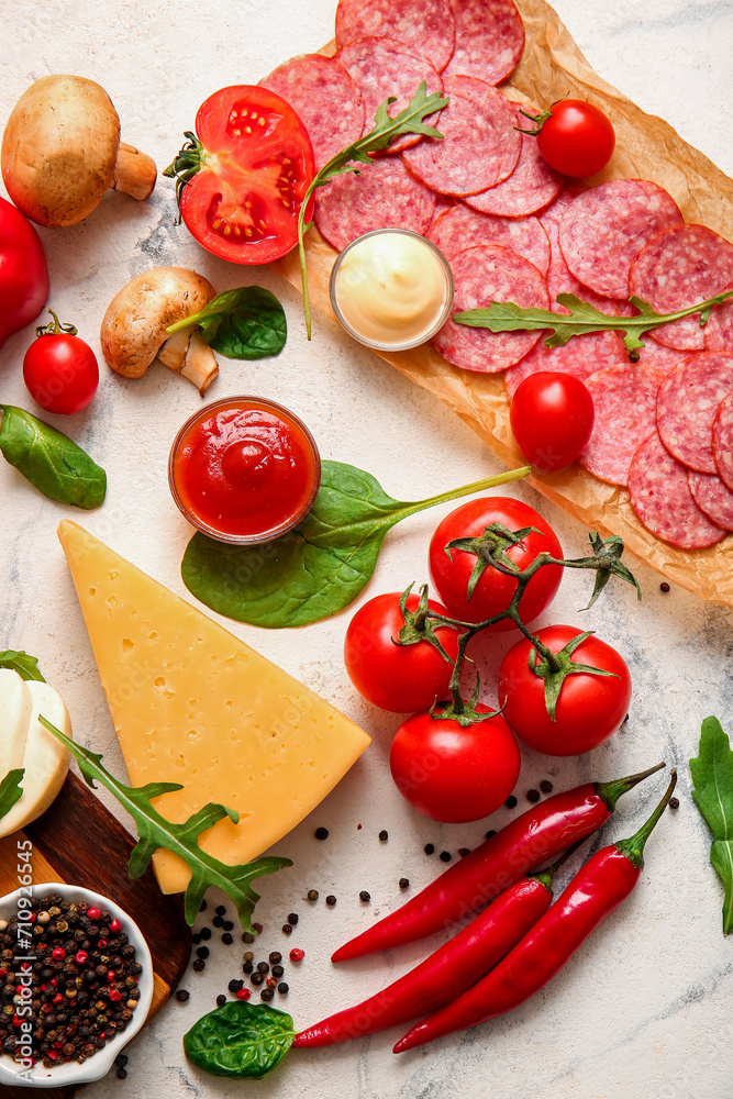 Different ingredients for preparing pizza on white marble background
