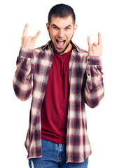 Sticker - Young handsome man wearing casual shirt shouting with crazy expression doing rock symbol with hands up. music star. heavy music concept.