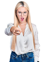 Wall Mural - Beautiful blonde woman wearing elegant shirt and glasses pointing displeased and frustrated to the camera, angry and furious with you