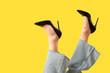 © Pixel-Shot - Legs of young woman in stylish black high heels on yellow background