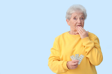 Sticker - Shocked senior woman with pills on blue background