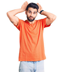 Wall Mural - Young handsome man with beard wearing casual t-shirt doing bunny ears gesture with hands palms looking cynical and skeptical. easter rabbit concept.