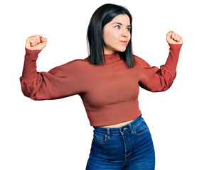 Poster - Young brunette woman with blue eyes wearing elegant sweater showing arms muscles smiling proud. fitness concept.