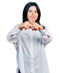 Poster - Young brunette woman with blue eyes wearing oversize white shirt rejection expression crossing fingers doing negative sign