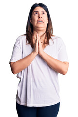 Sticker - Young beautiful brunette woman wearing casual t-shirt begging and praying with hands together with hope expression on face very emotional and worried. begging.