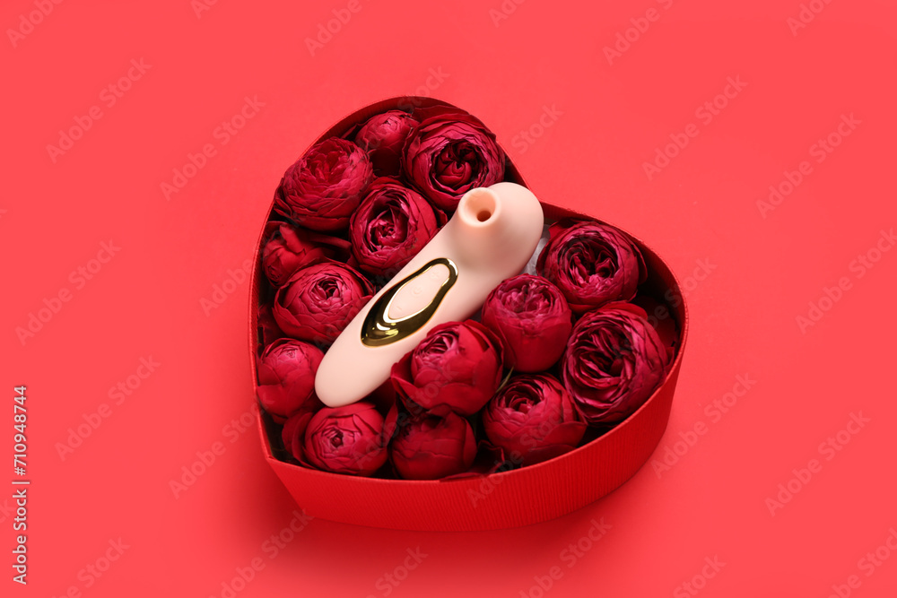 Gift box with beautiful rose flowers and vibrator on red background
