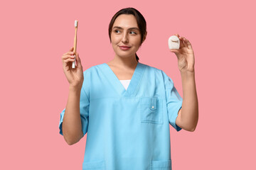 Poster - Young female dentist with dental floss and toothbrush on pink background