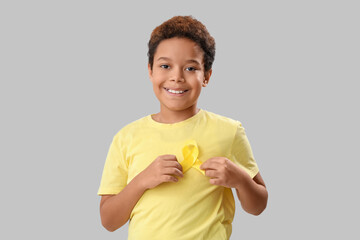 Poster - Cute little African-American boy with yellow ribbon on grey background. Childhood cancer awareness concept