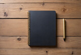 Black cover and gold spiral coil notebook isolated on rustic wooden table with plenty of copy space.