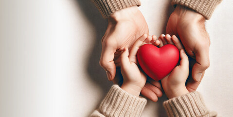 Adult and child hands holding red heart, family insurance, organ donation, love