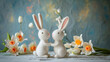 Two felt white bunnies kissing and holding hands on a spring decorated table. Soft colors, blurred blooms on background. Wool felted rabbits for cute, adorable scenery for Eastern card, or romance.