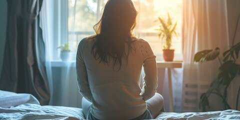 Poster - A woman sitting on a bed, gazing out of a window. Suitable for various lifestyle and introspection themes