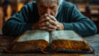 Mature man praying in front of bible