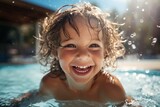 Fototapeta  - Ecstatic curly-haired kid in the swimming pool