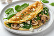 Egg omelette with spinach, mushrooms, and feta cheese on white plate