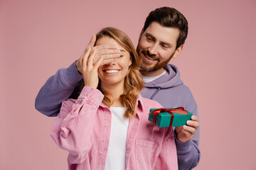 handsome smiling man holding gift box, closed eyes of young beautiful woman. portrait of happy roman