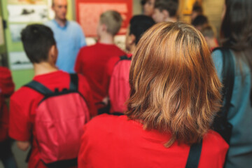 Group of students and school pupils in a science museum exhibition, excursion tour with guide, a docent with a tourist visitors, school field trip, attendees of technical museum exposition gallery