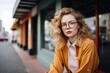 © Iigo - Portrait of a beautiful girl with curly hair in glasses and a yellow coat in the city