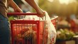 Closeup of a womans hand placing a reusable canvas bag into a shopping cart.