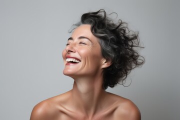 Portrait of a happy young woman laughing and looking up over gray background