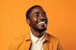 Portrait of a happy african american man laughing on orange background